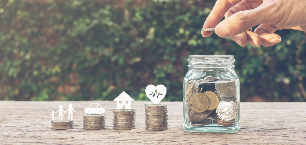 Managing money for family life concepts. Hand holding coin on a full money in glass jar and family member, car, house,healthy on coins. Depicts saving for wealth and life. fundraising concept.